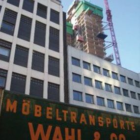 Ein Umzugsunternehmen vor einem modernen Bürogebäude mit Baukran im Hintergrund.