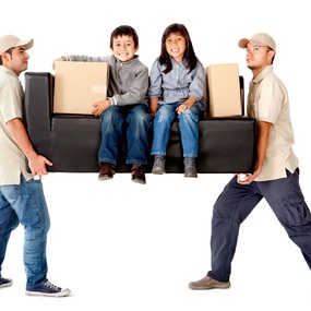 Zwei Umzugshelfer tragen ein Sofa mit zwei Kindern und Umzugskartons beim Möbeltransport.