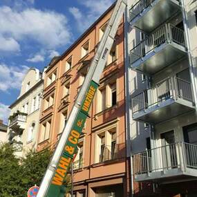 Umzugsaufzug transportiert Möbel an Balkon eines Mehrfamilienhauses bei Umzug.